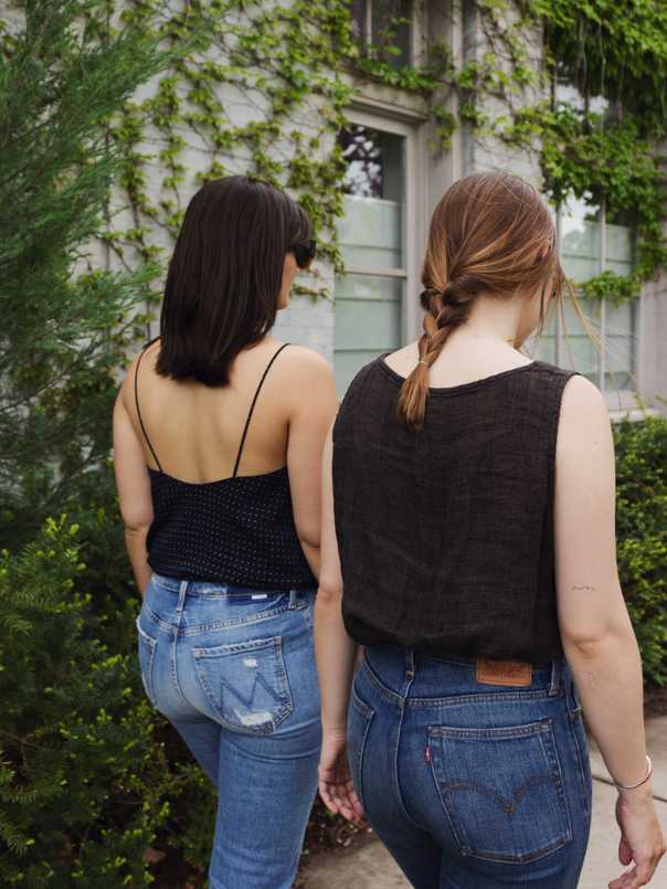 Sara wearing a navy polka dot tank and jeans and Jacqs wearing a brown linen tank and jeans