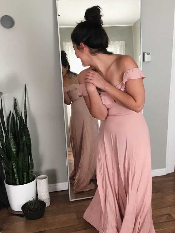 Sara in front of mirror in blush pink off-the-shoulder dress with ruffle neckline