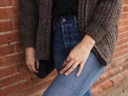 Detail of Jacqs wearing a cozy sweater and denim jeans