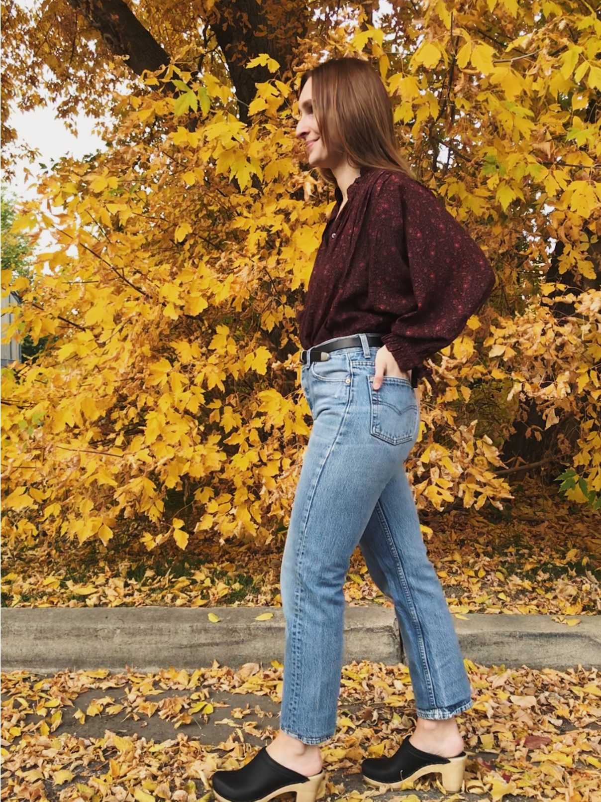 Jacqs wearing a burgundy floral blouse with vintage denim and black clogs