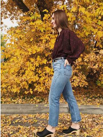 Jacqs wearing a burgundy floral blouse with vintage denim and black clogs