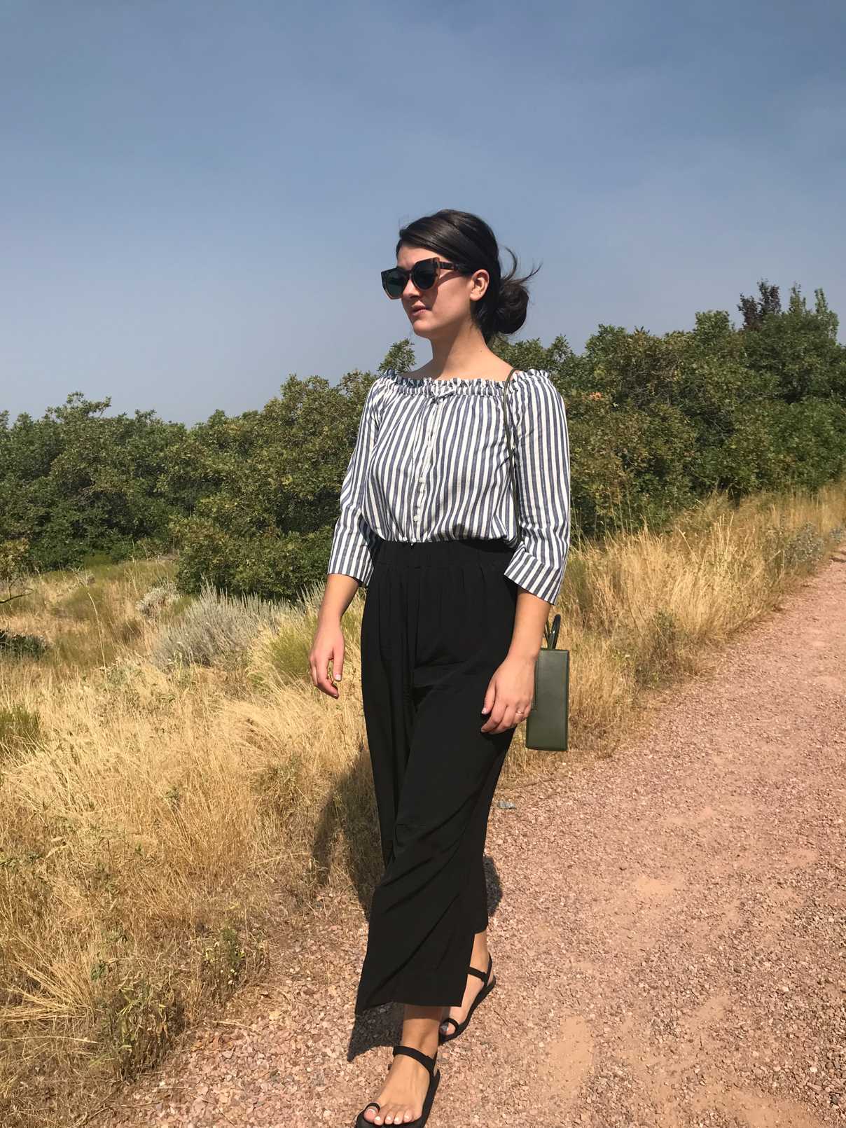 Sara wearing blue and white striped shirt, black wide leg pants, and black Xero Shoes sandals